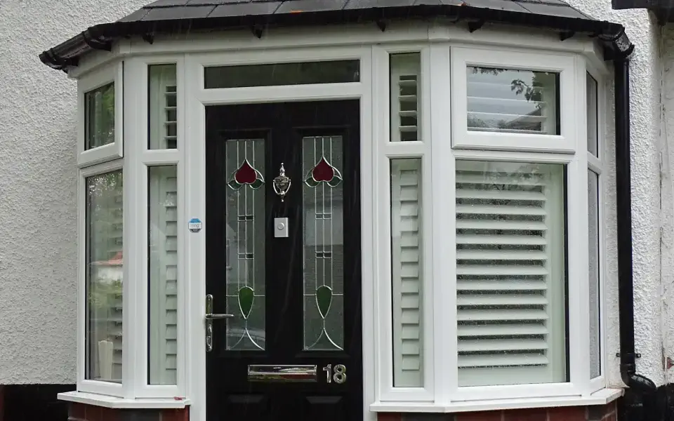 a front porch with a brown door having a heart design on its glass and a white-framed windows